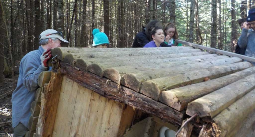 A group of people brace a wooden structure during a service project. 